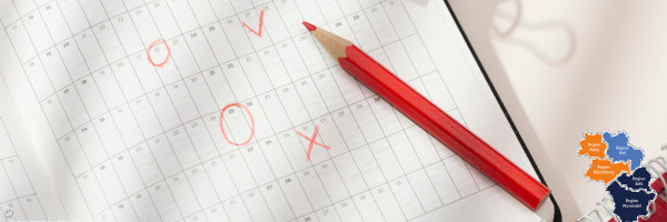 Roter Buntstift liegt auf einem Kalenderblatt